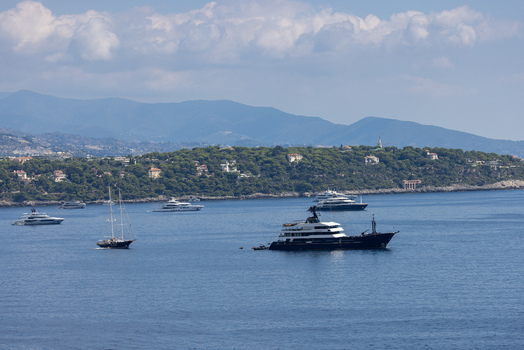 Aerial view of the Monaco City coastline with luxury yachts anchored in the Mediterranean Sea lush green hills and clear blue sky in Monaco Monaco.