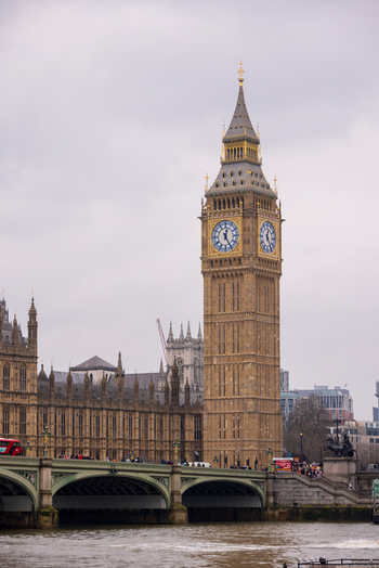London United Kingdom 12 May 2025 View of the Elizabeth Tower and Big Ben rising above the Palace of Westminster and Westminster Bridge under a cloudy sky.