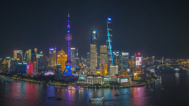 Aerial view of the illuminated Lujiazui skyline at night with the Oriental Pearl Tower and skyscrapers reflecting in the Huangpu River in Shanghai Shanghai China.