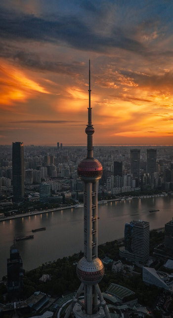 Aerial view of the Oriental Pearl Tower and the Lujiazui financial district skyline along the Huangpu River during a vibrant sunset in Shanghai Shanghai China.