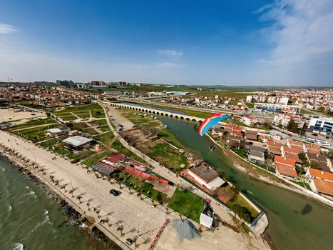 Aerial view of the historic Mimar Sinan Bridge spanning the river in Silivri with a paraglider flying overhead surrounded by urban rooftops and coastal landscape in Silivri Istanbul Turkey. Aerial view of the historic Mimar Sinan Bridge spanning the river in Silivri with a paraglider flying overhead surrounded by urban rooftops and coastal landscape in Silivri Istanbul Turkey.