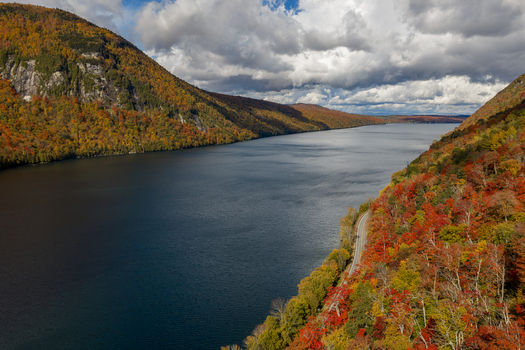 Aerial view of Lake Willoughby surrounded by vibrant autumn foliage on the steep mountainsides with a winding road along the shore in Westmore Vermont United States. Aerial view of Lake Willoughby surrounded by vibrant autumn foliage on the steep mountainsides with a winding road along the shore in Westmore Vermont United States.