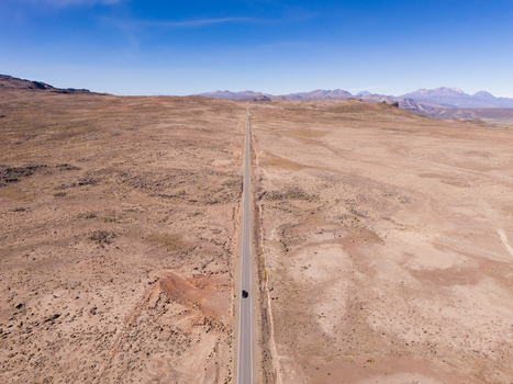 Aerial view of a long straight road cutting through the arid rocky landscape near Mirador de los Andes in Caylloma Arequipa Peru.