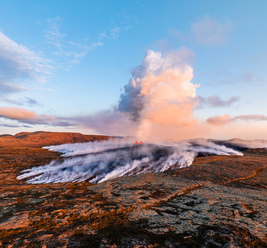 Aerial view of a volcanic eruption in Iceland with thick smoke and steam rising from the lava field across the rugged landscape under a golden sunset sky Iceland. Aerial view of a volcanic eruption in Iceland with thick smoke and steam rising from the lava field across the rugged landscape under a golden sunset sky Iceland.