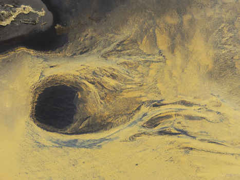 Aerial view of abstract patterns of orange sediment and a dark circular pool in a glacial river delta in Hallgeirseyjarvegur Rangarthing eystra Iceland. Aerial view of abstract patterns of orange sediment and a dark circular pool in a glacial river delta in Hallgeirseyjarvegur Rangarthing eystra Iceland.