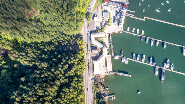 Aerial view of the marina with numerous boats docked at piers bordered by a lush green forest and a coastal road in Angra dos Reis Rio de Janeiro Brazil.