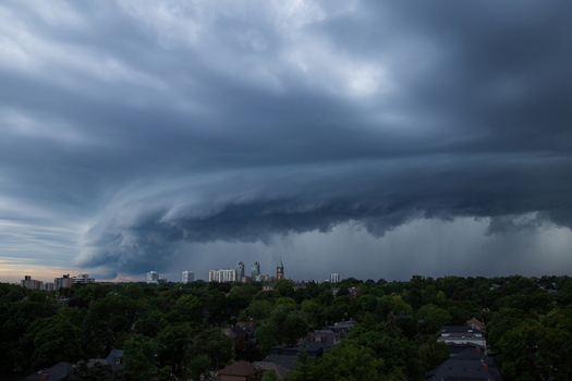 Aerial view of a dramatic shelf cloud approaching the city skyline over lush green residential neighborhoods Toronto Ontario Canada.