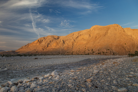 Aerial view of golden sunlight kissing the rugged peaks casting long shadows across the stony riverbed creating a stark contrast between light and shadow Pakistan. Aerial view of golden sunlight kissing the rugged peaks casting long shadows across the stony riverbed creating a stark contrast between light and shadow Pakistan.