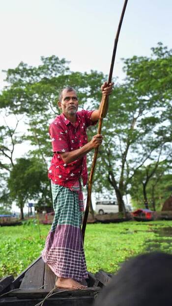 View of a fisherman navigating a wooden boat Bangladesh. View of a fisherman navigating a wooden boat Bangladesh.
