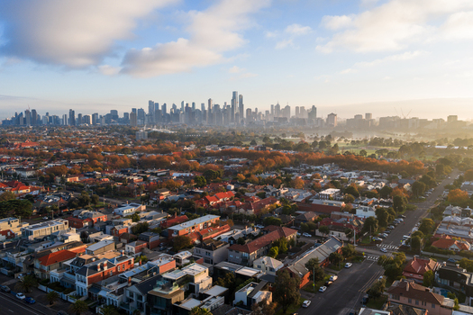 Aerial view of the Melbourne skyline at sunrise with residential rooftops autumn trees and urban streets in Melbourne Victoria Australia. Aerial view of the Melbourne skyline at sunrise with residential rooftops autumn trees and urban streets in Melbourne Victoria Australia.