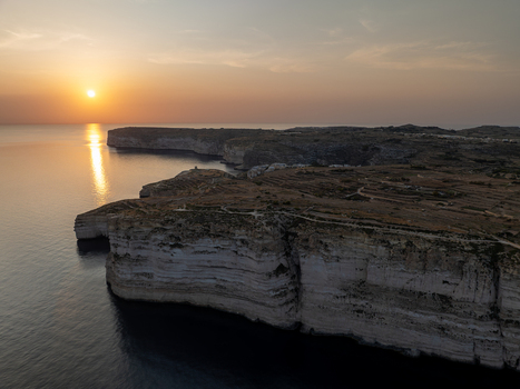 Aerial view of rugged cliffs meet the tranquil sun kissed sea creating a stunning contrast of textures and tones at Sanap Cliffs Munxar Gozo Malta. Aerial view of rugged cliffs meet the tranquil sun kissed sea creating a stunning contrast of textures and tones at Sanap Cliffs Munxar Gozo Malta.
