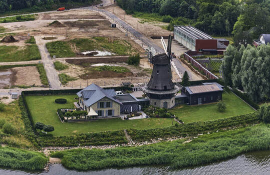 Schleswig Schleswig Holstein Germany 01 July 2026 Aerial view of Windmill Nicola and adjacent house on the redeveloped grounds of a former military base featuring lawns and waterfront.