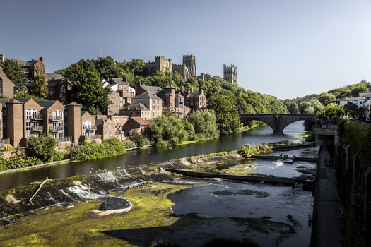 View of Durham Cathedral and Durham Castle overlooking the River Wear with historic stone buildings and a bridge in Durham England United Kingdom. View of Durham Cathedral and Durham Castle overlooking the River Wear with historic stone buildings and a bridge in Durham England United Kingdom.