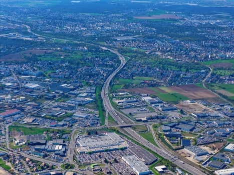 Aerial view of curving highways slicing through a blend of urban sprawl and verdant fields creating a tapestry of concrete and nature Sausheim Grand Est France.