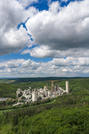 Aerial view of the Mokra cement plant with silos and chimneys surrounded by dense green forests under a cloudy sky Mokra Horakov Jihomoravsky kraj Czechia. Aerial view of the Mokra cement plant with silos and chimneys surrounded by dense green forests under a cloudy sky Mokra Horakov Jihomoravsky kraj Czechia.