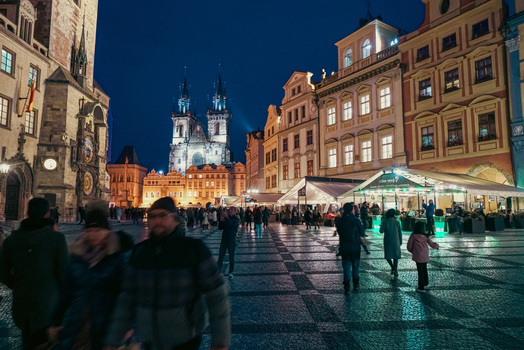 Prague Czechia 03 November 2021 View of the Church of Our Lady before Tyn illuminated at night in the Old Town Square with people walking on cobblestones. Prague Czechia 03 November 2021 View of the Church of Our Lady before Tyn illuminated at night in the Old Town Square with people walking on cobblestones.