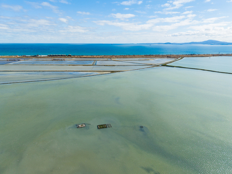 Aerial view of Lake Atanasovsko featuring salt pans and shallow waters under a blue sky with the Black Sea in the distance Burgas Burgas Bulgaria. Aerial view of Lake Atanasovsko featuring salt pans and shallow waters under a blue sky with the Black Sea in the distance Burgas Burgas Bulgaria.