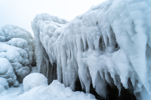 View of the ice covered Molenfeuer Sassnitz lighthouse structure with thick icicles and frozen formations along the Baltic Sea coast in Sassnitz Mecklenburg Vorpommern Germany.