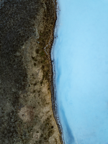 Aerial view of the bright blue geothermal waters of the Reykjanes peninsula contrasting with dark volcanic terrain in Grindavikurbaer Iceland. Aerial view of the bright blue geothermal waters of the Reykjanes peninsula contrasting with dark volcanic terrain in Grindavikurbaer Iceland.