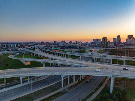 Aerial view of a complex highway interchange with multiple overpasses and the city skyline under a sunset sky in Louisville Kentucky United States.