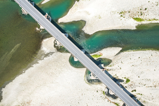 Aerial view of the Ponte Crescentino bridge spanning a river with low water levels and exposed gravel banks due to drought in Verrua Savoia Piemonte Italy. Aerial view of the Ponte Crescentino bridge spanning a river with low water levels and exposed gravel banks due to drought in Verrua Savoia Piemonte Italy.