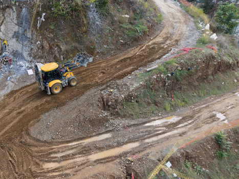 Aerial view of a yellow backhoe loader working on a muddy construction site with tire tracks and excavated earth in Istanbul Istanbul Turkiye. Aerial view of a yellow backhoe loader working on a muddy construction site with tire tracks and excavated earth in Istanbul Istanbul Turkiye.
