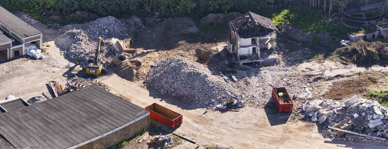 Schleswig Germany 26 June 2026 Aerial view of the former Butterwerken butter factory demolition site with a yellow excavator rubble piles a ruined building and red dumpsters. Schleswig Germany 26 June 2026 Aerial view of the former Butterwerken butter factory demolition site with a yellow excavator rubble piles a ruined building and red dumpsters.