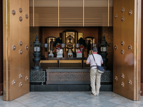 View of a man standing in front of a golden temple with intricate carvings offering a prayer in a serene atmosphere Narita Chiba Japan. View of a man standing in front of a golden temple with intricate carvings offering a prayer in a serene atmosphere Narita Chiba Japan.