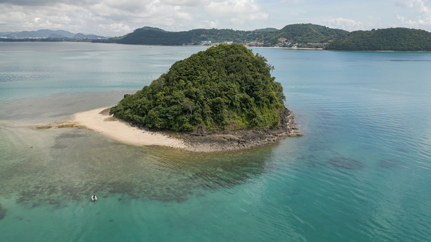 Aerial view of a small lush green tropical island with a sandy beach surrounded by clear turquoise water and a small boat in the sea Thailand. Aerial view of a small lush green tropical island with a sandy beach surrounded by clear turquoise water and a small boat in the sea Thailand.