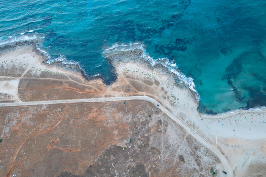 Aerial view of the Riserva Naturale Orientata dello Zingaro coastline with turquoise waters rocky cliffs and a coastal road in San Vito Lo Capo Sicilia Italy. Aerial view of the Riserva Naturale Orientata dello Zingaro coastline with turquoise waters rocky cliffs and a coastal road in San Vito Lo Capo Sicilia Italy.