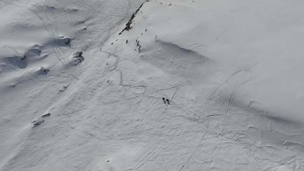 Aerial view of hikers on snowy slopes in Italy.