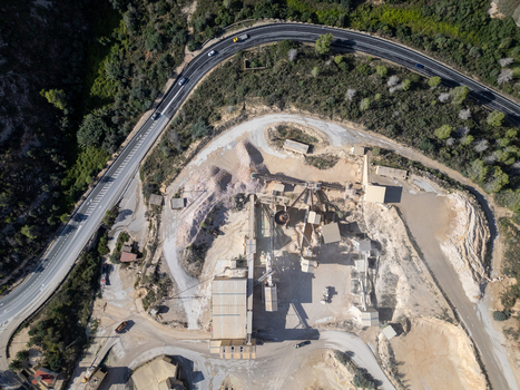 Aerial view of a quarry site with industrial machinery conveyor belts and surrounding roads in Teulada Valencian Community Spain.