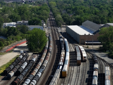 Aerial view of freight trains and tanker cars parked on multiple tracks in an industrial rail yard surrounded by green trees Cincinnati OH United States. Aerial view of freight trains and tanker cars parked on multiple tracks in an industrial rail yard surrounded by green trees Cincinnati OH United States.