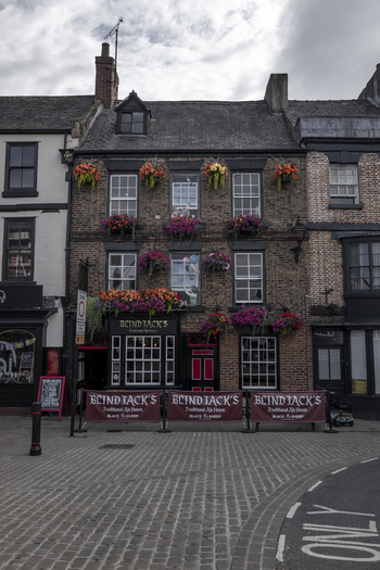 Knaresborough United Kingdom 14 July 2026 View of the historic Blind Jack s pub with vibrant hanging flower baskets and traditional signage on a cobblestone street.