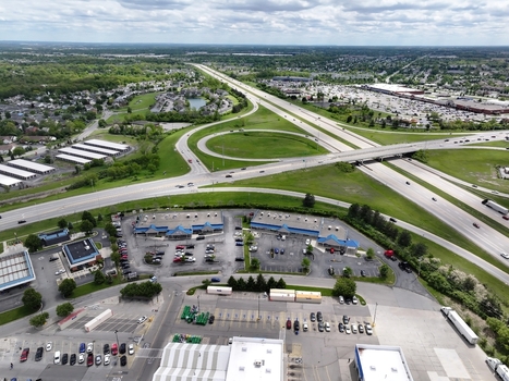 Aerial view of a highway interchange with vehicles commercial parking lots and suburban residential neighborhoods under a cloudy sky Columbus Ohio United States. Aerial view of a highway interchange with vehicles commercial parking lots and suburban residential neighborhoods under a cloudy sky Columbus Ohio United States.
