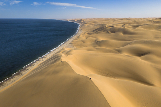 Aerial view of golden dunes meet the deep blue sea creating a stark contrast of colors and textures along the coastline Anichab Erongo Namibia. Aerial view of golden dunes meet the deep blue sea creating a stark contrast of colors and textures along the coastline Anichab Erongo Namibia.