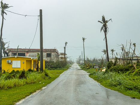 San Jose Tinian Northern Mariana Islands 06 July 2026 View of a road showing the aftermath of a severe storm with damaged palm trees debris and a yellow building. San Jose Tinian Northern Mariana Islands 06 July 2026 View of a road showing the aftermath of a severe storm with damaged palm trees debris and a yellow building.