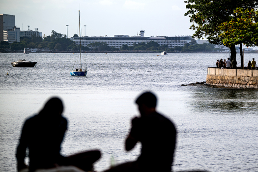 Rio de Janeiro Brazil 14 June 2026 View of people sitting at Mureta da Urca overlooking Guanabara Bay with sailboats and the city skyline in the background.
