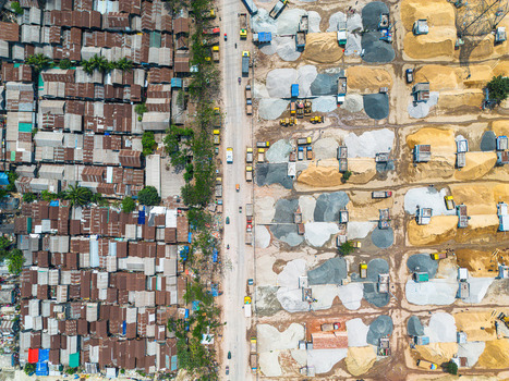 Aerial view of corrugated iron roofs contrast sharply with piles of sand and gravel bisected by a busy road Dhaka Dhaka Division Bangladesh. Aerial view of corrugated iron roofs contrast sharply with piles of sand and gravel bisected by a busy road Dhaka Dhaka Division Bangladesh.