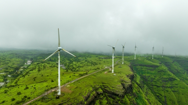 Aerial view of wind turbines standing on lush green hills under a cloudy sky in Igatpuri Maharashtra India. Aerial view of wind turbines standing on lush green hills under a cloudy sky in Igatpuri Maharashtra India.
