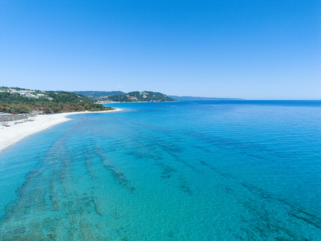 Aerial view of Possidi Beach with turquoise waters white sand and lush green hills under a clear blue sky Greece.