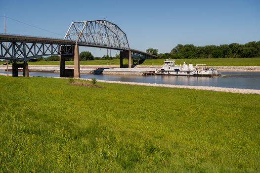 View of the historic Old Chain of Rocks Bridge spanning the Mississippi River with a towboat pushing barges in St. Louis Missouri United States. View of the historic Old Chain of Rocks Bridge spanning the Mississippi River with a towboat pushing barges in St. Louis Missouri United States.