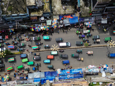 Rajshahi Bangladesh 26 September 2026 Aerial view of a busy street filled with colorful rickshaws cars and pedestrians with vibrant market stalls and umbrellas lining the roadside. Rajshahi Bangladesh 26 September 2026 Aerial view of a busy street filled with colorful rickshaws cars and pedestrians with vibrant market stalls and umbrellas lining the roadside.