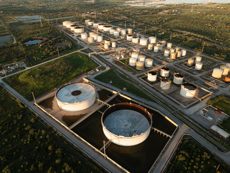 Aerial view of large industrial oil storage tanks and refinery facilities surrounded by green fields in Augusta Sicily Italy. Aerial view of large industrial oil storage tanks and refinery facilities surrounded by green fields in Augusta Sicily Italy.