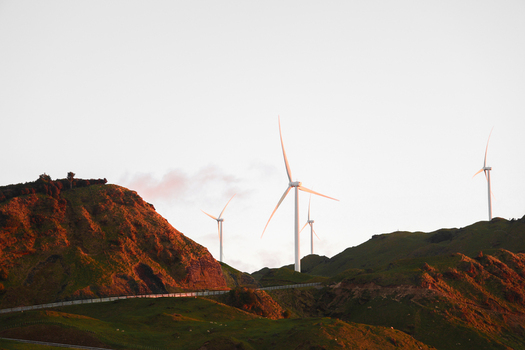 Aerial view of Harapaki Wind Farm with wind turbines on rolling green hills during sunset in Te Haroto Hawke s Bay Region New Zealand.