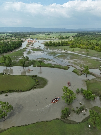 Aerial view of the winding river and lush wetlands with small boats carrying passengers through the calm waters surrounded by green fields and trees in Sitakund Chittagong Division Bangladesh. Aerial view of the winding river and lush wetlands with small boats carrying passengers through the calm waters surrounded by green fields and trees in Sitakund Chittagong Division Bangladesh.