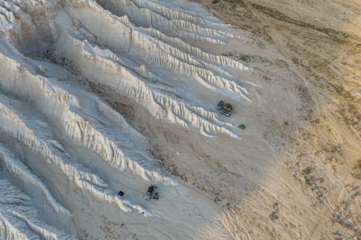Aerial view of the white chalk formations of Tuzbair with parked vehicles and tents in the desert landscape of Mangystau District Mangystau Region Kazakhstan.