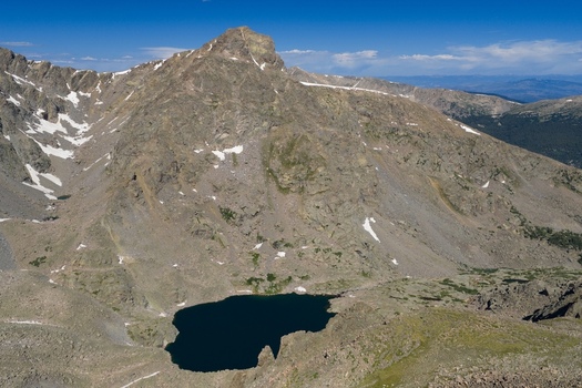 Aerial view of Mount of the Holy Cross in the Sawatch Range featuring rugged rocky slopes patches of snow and a deep blue alpine lake in Vail Colorado United States. Aerial view of Mount of the Holy Cross in the Sawatch Range featuring rugged rocky slopes patches of snow and a deep blue alpine lake in Vail Colorado United States.