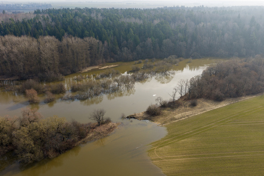 Aerial view of a flooded river valley with submerged trees dense forest and agricultural fields under a hazy sky Kaniukai Kaunas County Lithuania. Aerial view of a flooded river valley with submerged trees dense forest and agricultural fields under a hazy sky Kaniukai Kaunas County Lithuania.