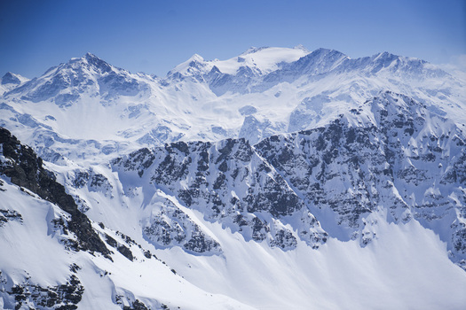 Aerial view of the snow capped peaks and jagged rocky ridges of La Rosiere under a clear blue sky in Montvalezan Auvergne Rhone Alpes France.